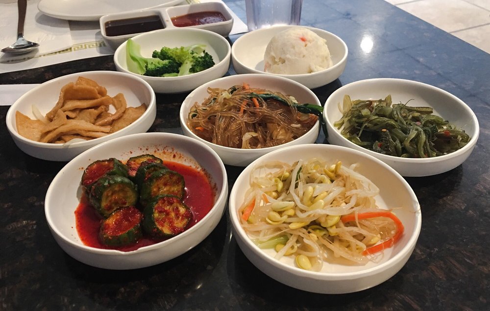 Bowls of banchan: bean sprouts, cucumber kimchi, japchae and pickled radish