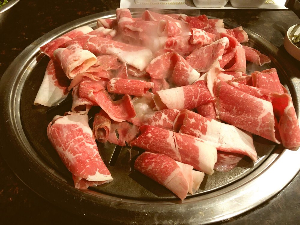 Thin-sliced brisket rolled out on the tabletop grill
